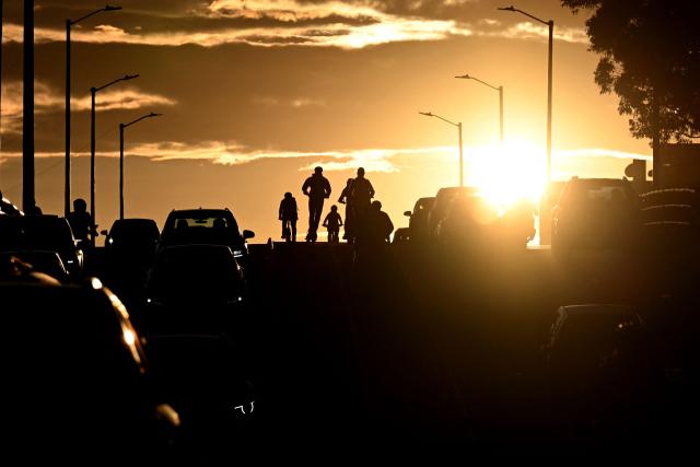 Cyclists ride past a traffic jam during sunset in Bogota on April 20, 2026. (Photo by Pablo VERA / AFP)