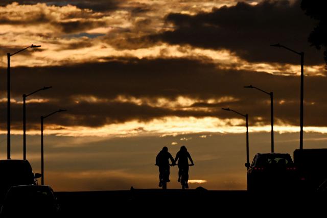Cyclists ride during sunset in Bogota on April 20, 2026. (Photo by Pablo VERA / AFP)