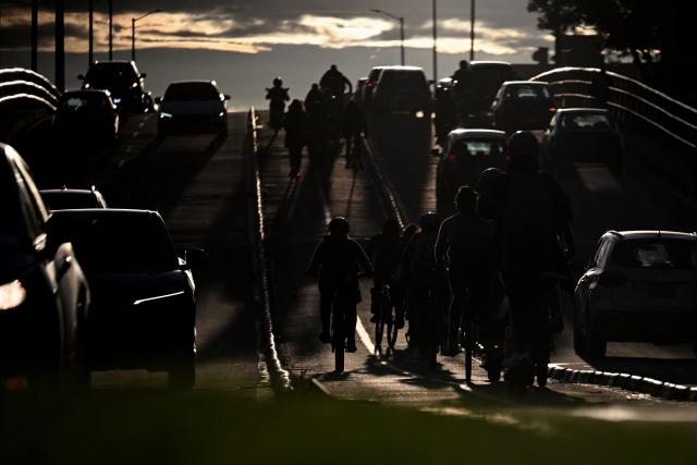 Cyclists ride past a traffic jam before sunset in Bogota on April 20, 2026. (Photo by Pablo VERA / AFP)
