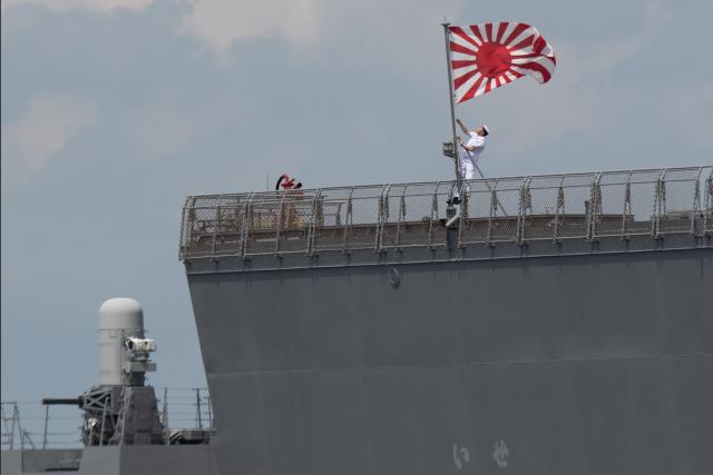 (FILES) A sailor raises the Japan Maritime Self-Defence Force ensign on board the JS Ise, a Hyuga-class helicopter destroyer, as it docks at the international port in Manila on June 21, 2025. Japan's top government spokesman Minoru Kihara said on April 21, 2026, that Tokyo would ease decades-old arms export rules, paving the way for the sale of lethal weapons overseas. (Photo by Ted ALJIBE / AFP)