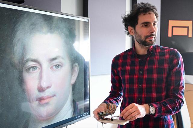 Grigore Burloiu, a lecturer in interactive technologies, uses a DIY accelerometer made by himself to generate AI morphed portraits during a class at the National University of Theatre and Film in Bucharest on March 4, 2026. AI is "really good" at focusing in on people's music consumption, so on what the industry usually offers, according to him. "No one woke up overnight and said: 'That's it, I like AI'... AI is all about finding the lowest common denominator". (Photo by Daniel MIHAILESCU / AFP)