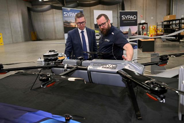 Australia's Minister for Defence Industry Pat Conroy (L) inspects a maritime surveillance drone with SYPAQ Systems chief engineer Ross Osborne as the Australian Government announces it will invest 5 billion USD over the next decade in counter drones for the Australian Defence Force (ADF), in Melbourne on April 21, 2026 (Photo by William WEST / AFP)