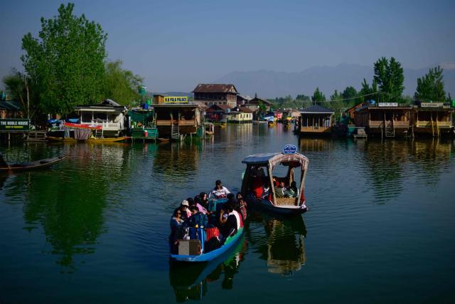 Tourists ride Shikara, a traditional wooden boat, at the iconic Dal Lake in Srinagar on April 21, 2026. In the once-booming resort towns of India-controlled Kashmir, hoteliers are switching on the lights to welcome a trickle of visitors, a year after militants opened fire on holidaymakers in an attack that killed 26 people. (Photo by MANAN VATSYAYANA / AFP)