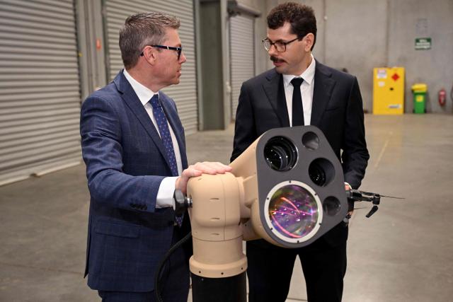 Australia's Minister for Defence Industry Pat Conroy (L) inspects a AIM Defence Fractl:1 counter-drone laser system with AIM Defence Co-CEO Jae Daniel (R) as the Australian Government announces it will invest 5 billion USD over the next decade in counter drones for the Australian Defence Force (ADF), in Melbourne on April 21, 2026 (Photo by William WEST / AFP)