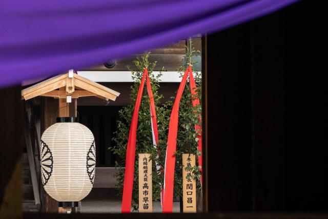 A wooden plaque bearing the name of Japan’s Prime Minister Sanae Takaichi (L) is seen beside a “masakaki” tree that she sent as an offering to the Yasukuni Shrine on the first day of the Spring Festival in Tokyo on April 21, 2026. (Photo by Yuichi YAMAZAKI / AFP)