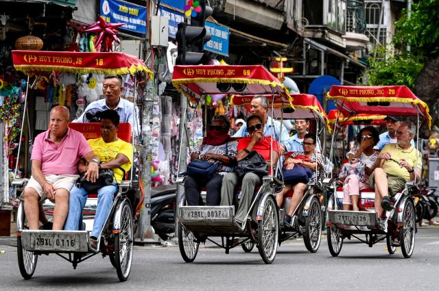 Tourists ride cyclos along a street in Hanoi on April 21, 2026. (Photo by Nhac NGUYEN / AFP)
