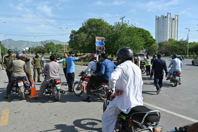 Security personnel guide commuters for alternate routes from a checkpoint near the Serena Hotel at the Red Zone area in Islamabad on April 21, 2026, amid heightened security measures ahead of US-Iran peace talks. Pakistan's Prime Minister Shehbaz Sharif said on April 19 he had spoken by phone with Iranian President Masoud Pezeshkian ahead of anticipated US-Iran talks in Islamabad, and reaffirmed his government's readiness to mediate the conflict. US President Donald Trump is sending negotiators to Pakistan on April 20 for talks with Iran just days before a ceasefire in the Middle East expires, though Tehran has reportedly yet to decide whether it will participate. (Photo by Asif HASSAN / AFP)