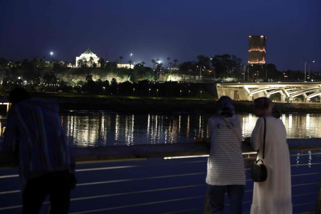 People stand looking across the river at the skyline in the costal city of Rabat on April 20, 2026. (Photo by Abdel Majid BZIOUAT / AFP)