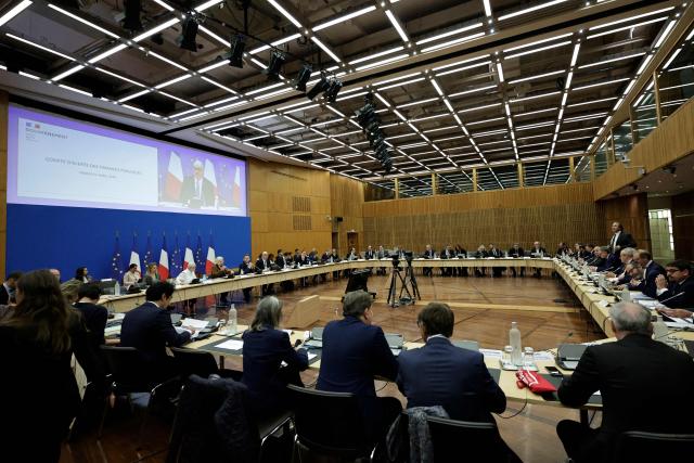 France's Economy, Finances and Industry Minister Roland Lescure (C and on screen) delivers a speech at the opening of the public finances alert committee at the Ministry of Economics and Finance in Paris on April 21, 2026. (Photo by STEPHANE DE SAKUTIN / AFP)