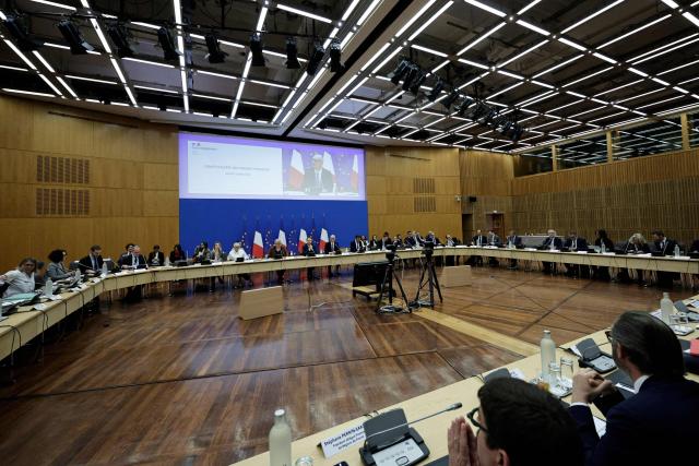 France's Economy, Finances and Industry Minister Roland Lescure (C and on screen) delivers a speech at the opening of the public finances alert committee at the Ministry of Economics and Finance in Paris on April 21, 2026. (Photo by STEPHANE DE SAKUTIN / AFP)