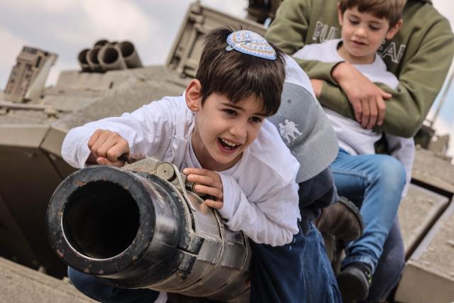 Children with their families climb atop old tanks and military vehicles at the Israeli Armoured Corps memorial in Latrun, between Jerusalem and Tel Aviv, on April 21, 2026, the day after Israel commemorates Remembrance Day for fallen soldiers or Yom HaZikaron. At sunset on April 20, gatherings at military cemeteries and war memorials took place to commemorate Remembrance Day which gives way to public performances, street parties and general merrymaking to mark 78 years since the declaration of the Israeli state in 1948. (Photo by Jack GUEZ / AFP)