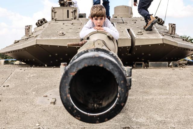 A child climbs atop old tanks and military vehicles at the Israeli Armoured Corps memorial in Latrun, between Jerusalem and Tel Aviv, on April 21, 2026, the day after Israel commemorates Remembrance Day for fallen soldiers or Yom HaZikaron. At sunset on April 20, gatherings at military cemeteries and war memorials took place to commemorate Remembrance Day which gives way to public performances, street parties and general merrymaking to mark 78 years since the declaration of the Israeli state in 1948. (Photo by Jack GUEZ / AFP)
