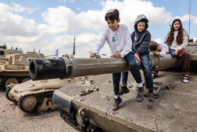 Children with their families climb atop old tanks and military vehicles at the Israeli Armoured Corps memorial in Latrun, between Jerusalem and Tel Aviv, on April 21, 2026, the day after Israel commemorates Remembrance Day for fallen soldiers or Yom HaZikaron. At sunset on April 20, gatherings at military cemeteries and war memorials took place to commemorate Remembrance Day which gives way to public performances, street parties and general merrymaking to mark 78 years since the declaration of the Israeli state in 1948. (Photo by Jack GUEZ / AFP)