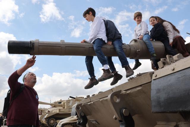 Children with their families climb atop old tanks and military vehicles at the Israeli Armoured Corps memorial in Latrun, between Jerusalem and Tel Aviv, on April 21, 2026, the day after Israel commemorates Remembrance Day for fallen soldiers or Yom HaZikaron. At sunset on April 20, gatherings at military cemeteries and war memorials took place to commemorate Remembrance Day which gives way to public performances, street parties and general merrymaking to mark 78 years since the declaration of the Israeli state in 1948. (Photo by Jack GUEZ / AFP)