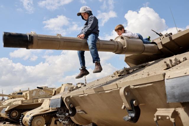 Children with their families climb atop old tanks and military vehicles at the Israeli Armoured Corps memorial in Latrun, between Jerusalem and Tel Aviv, on April 21, 2026, the day after Israel commemorates Remembrance Day for fallen soldiers or Yom HaZikaron. At sunset on April 20, gatherings at military cemeteries and war memorials took place to commemorate Remembrance Day which gives way to public performances, street parties and general merrymaking to mark 78 years since the declaration of the Israeli state in 1948. (Photo by Jack GUEZ / AFP)