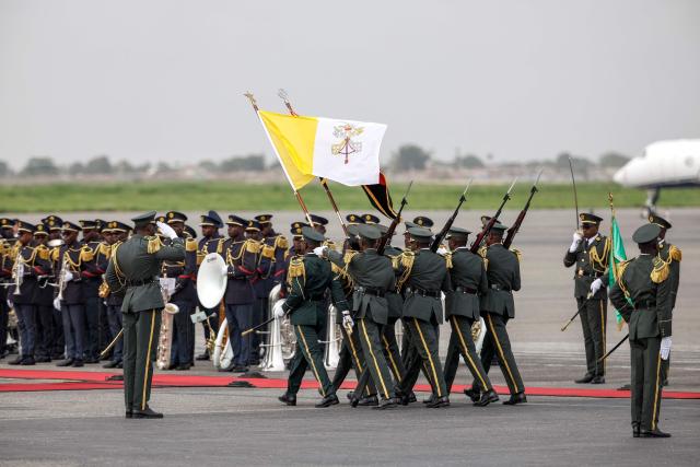 Members of the ceremonial guard carry Vatican and Angola flags ahead of the farewell ceremony of Pope Leo XIV at the "4 de Fevereiro" Luanda International Airport in Luanda on the ninth day of an 11-day apostolic journey to Africa, on April 21, 2026. (Photo by PHILL MAGAKOE / AFP)