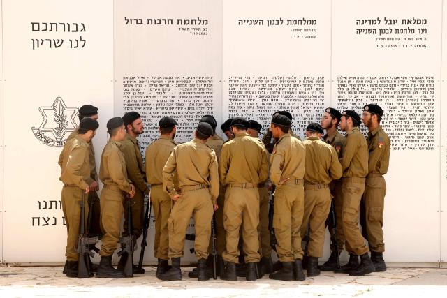 TOPSHOT - Israelis soldiers gather in front of a commemorative plaque honoring fallen Israeli soldiers at the Armoured Corps Memorial, following a ceremony to mark Remembrance Day (or Memorial Day) in Latrun, between Jerusalem and Tel Aviv on April 21, 2026. At sunset on April 20, gatherings at military cemeteries and war memorials took place to commemorate Remembrance Day which gives way to public performances, street parties and general merrymaking to mark 78 years since the declaration of the Israeli state in 1948. (Photo by Jack GUEZ / AFP)