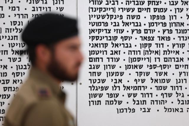 A Israeli soldier walks past a commemorative plaque honoring fallen Israeli soldiers at the Armoured Corps Memorial, following a ceremony to mark Remembrance Day (or Memorial Day) in Latrun, between Jerusalem and Tel Aviv on April 21, 2026. At sunset on April 20, gatherings at military cemeteries and war memorials took place to commemorate Remembrance Day which gives way to public performances, street parties and general merrymaking to mark 78 years since the declaration of the Israeli state in 1948. (Photo by Jack GUEZ / AFP)