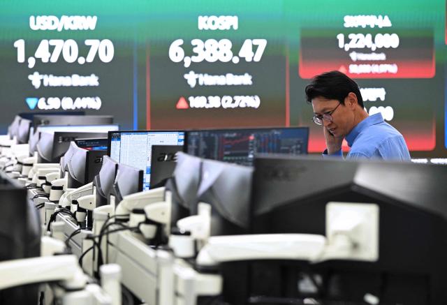 A currency dealer monitors exchange rates as a screen shows South Korea's benchmark stock index (KOSPI) and the Korean won/USD exchange rate in a foreign exchange dealing room at the Hana Bank headquarters in Seoul on April 21, 2026. South Korea's benchmark Kospi stock index closed at a record high on April 21 as a rally in tech firms helped it recover the steep losses suffered during a rout triggered by the war in the Middle East. (Photo by Jung Yeon-je / AFP)