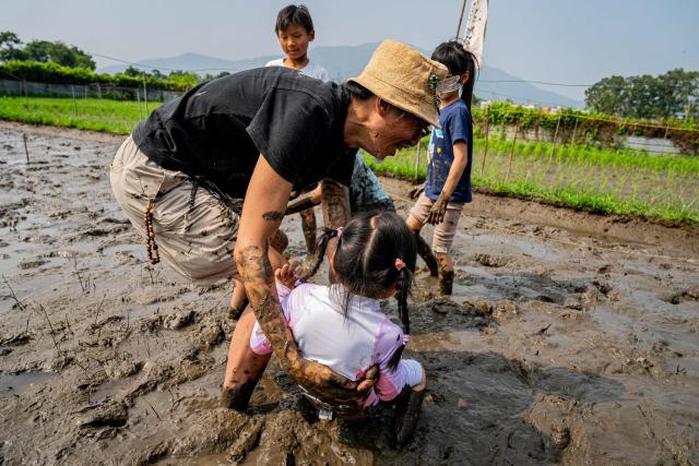 A man joins children in a mud wrestling activity as part of an organised event, involving mud races and wrestling matches, in Hong Kong on April 18, 2026. (Photo by Leung Man Hei / AFP)