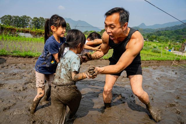 A man joins children in a mud wrestling activity in a muddy field during an organised event, involving mud races and wrestling matches, in Hong Kong on April 18, 2026. (Photo by Leung Man Hei / AFP)