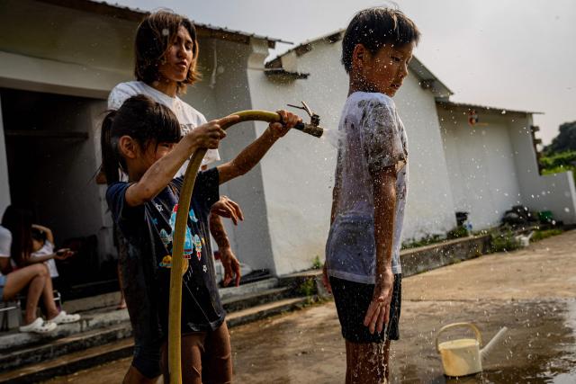 Participants wash off mud after taking part in muddy field activities during an organised event, involving mud races and wrestling matches, in Hong Kong on April 18, 2026. (Photo by Leung Man Hei / AFP)