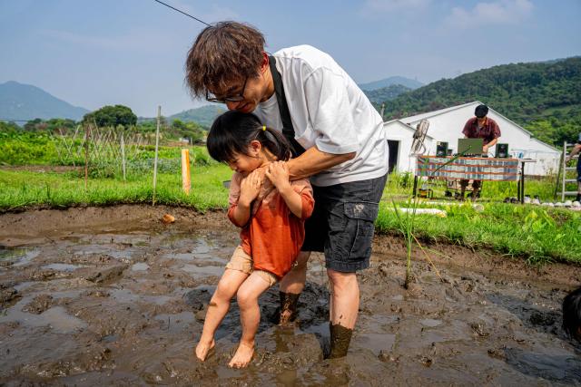 Participants gradually enter a muddy field for a trial experience ahead of an organised event, involving mud races and wrestling matches, in Hong Kong on April 18, 2026. (Photo by Leung Man Hei / AFP)