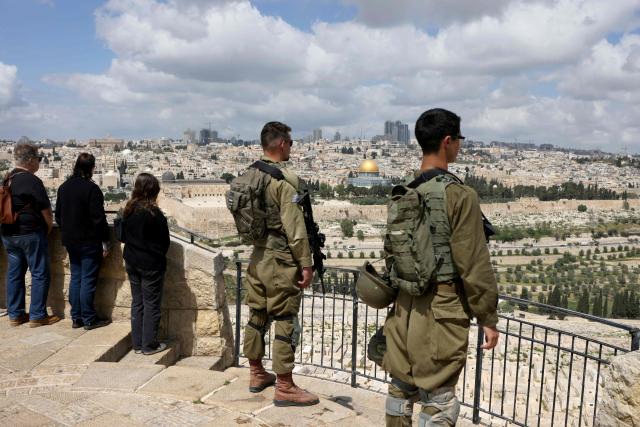 Israelis observe two minutes of silence as they stand on the Mount of Olives overlooking Jerusalem's Old City and Islam's Dome of the Rock as they mark Remembrance Day, which commemorates Israel's fallen soldiers, in Jerusalem on April 21, 2026. (Photo by AHMAD GHARABLI / AFP)