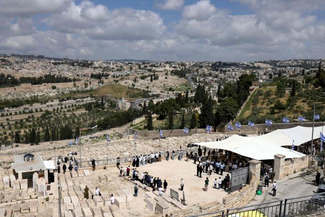 Israelis observe two minutes of silence as they stand on the Mount of Olives overlooking Jerusalem's Old City as they mark Remembrance Day, which commemorates Israel's fallen soldiers, in Jerusalem on April 21, 2026. (Photo by AHMAD GHARABLI / AFP)
