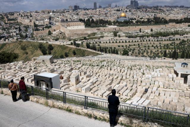 Israelis observe two minutes of silence as they stand on the Mount of Olives overlooking Jerusalem's Old City and Islam's Dome of the Rock as they mark Remembrance Day, which commemorates Israel's fallen soldiers, in Jerusalem on April 21, 2026. (Photo by AHMAD GHARABLI / AFP)