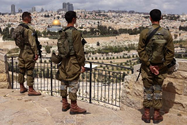 Israelis observe two minutes of silence as they stand on the Mount of Olives overlooking Jerusalem's Old City and Islam's Dome of the Rock as they mark Remembrance Day, which commemorates Israel's fallen soldiers, in Jerusalem on April 21, 2026. (Photo by AHMAD GHARABLI / AFP)