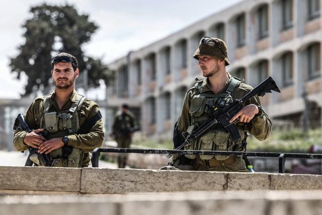 Israeli soldiers observe two minutes of silence as they stand on the Mount of Olives overlooking Jerusalem's Old City and Islam's Dome of the Rock as they mark Remembrance Day, which commemorates Israel's fallen soldiers, in Jerusalem on April 21, 2026. (Photo by Ahmad GHARABLI / AFP)
