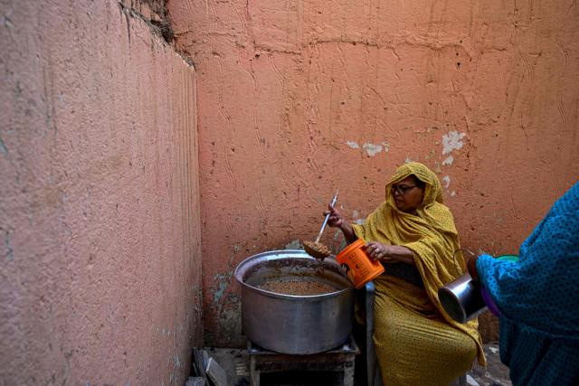 A Sudanese woman prepares a free meal canister at the home of the founder of the “Community Kitchen” initiative in Omdurman on April 21, 2026. The top United Nations official in Sudan told AFP on April 16, 2026, that the country, facing the world's largest humanitarian crisis, has been "abandoned" as the war between the army and the paramilitary Rapid Support Forces (RSF) enters its fourth year. (Photo by Khaled DESOUKI / AFP)