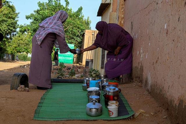 Sudanese women arrange containers filled with free food placed in front of the home of the founder of the “Community Kitchen” initiative, in Omdurman on April 21, 2026. The top United Nations official in Sudan told AFP on April 16, 2026, that the country, facing the world's largest humanitarian crisis, has been "abandoned" as the war between the army and the paramilitary Rapid Support Forces (RSF) enters its fourth year. (Photo by Khaled DESOUKI / AFP)