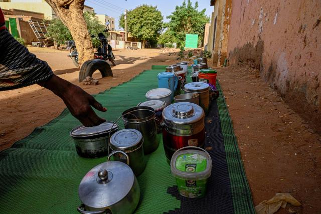 A Sudanese woman chooses a container filled with free food placed in front of the home of the founder of the “Community Kitchen” initiative, in Omdurman on April 21, 2026. The top United Nations official in Sudan told AFP on April 16, 2026, that the country, facing the world's largest humanitarian crisis, has been "abandoned" as the war between the army and the paramilitary Rapid Support Forces (RSF) enters its fourth year. (Photo by Khaled DESOUKI / AFP)
