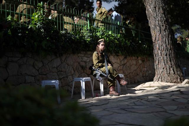 An Israeli soldier sits at the Military Cemetery on Mount Herzl as people gather to commemorate Israel's Remembrance Day for fallen soldiers or Yom HaZikaron, in Jerusalem on April 21, 2026. (Photo by Ilia YEFIMOVICH / AFP)