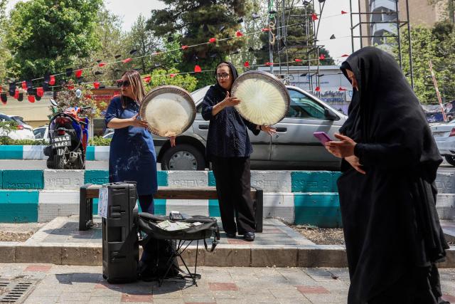 TOPSHOT - Musicians perform on a street in Tehran on April 21, 2026, amid a ceasefire in the region. With the end of a two-week ceasefire approaching, the White House said US Vice President JD Vance was ready to return to Pakistan for fresh negotiations to end a conflict that has sent crude soaring and revived inflation fears. (Photo by AFP) / 