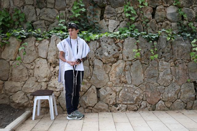 An Israeli wearing a prayer shawl prays as people gather at the Military Cemetery on Mount Herzl commemorating Israel's Remembrance Day for fallen soldiers or Yom HaZikaron, in Jerusalem on April 21, 2026. (Photo by Ilia YEFIMOVICH / AFP)