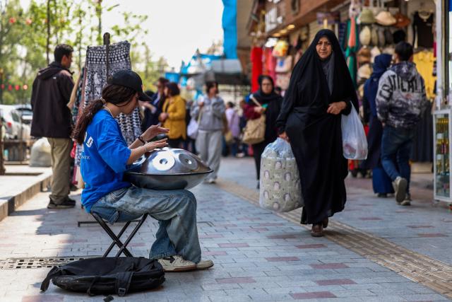 TOPSHOT - A musician plays a hang drum on a street in Tehran on April 21, 2026, amid a ceasefire in the region. With the end of a two-week ceasefire approaching, the White House said US Vice President JD Vance was ready to return to Pakistan for fresh negotiations to end a conflict that has sent crude soaring and revived inflation fears. (Photo by AFP) / 