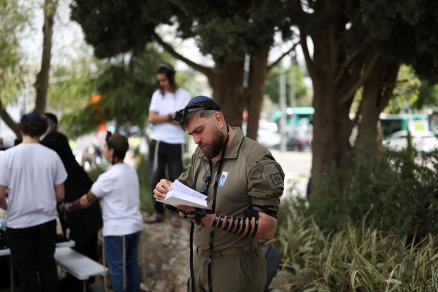A soldier prays as Israelis gather at the Military Cemetery on Mount Herzl commemorating Israel's Remembrance Day for fallen soldiers or Yom HaZikaron, in Jerusalem on April 21, 2026. (Photo by Ilia YEFIMOVICH / AFP)