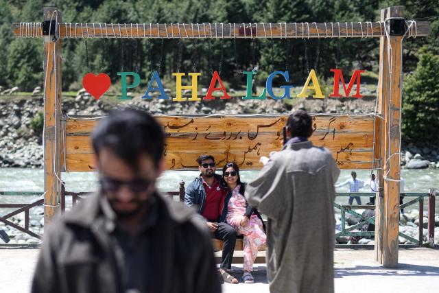 Tourists take photographs infront of “I Love Pahalgam“ signage along the banks of Lidder river in Pahalgam in south Kashmir’s Anantnag district on April 21, 2026. Relations between nuclear-armed neighbours India and Pakistan plummeted last year after an attack in Indian-administered Kashmir killed 26 men, mostly Hindu tourists, leading to their worst conflict in decades. Gunmen burst out of forests near the resort town of Pahalgam on April 22, 2025 and raked crowds of visitors with automatic weapons. (Photo by MANAN VATSYAYANA / AFP)