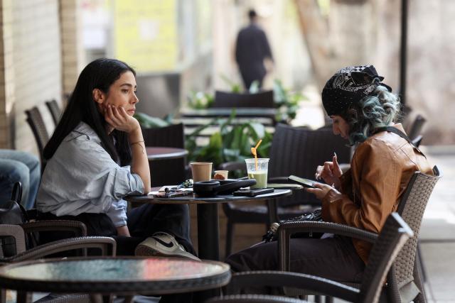 Two women sit at a cafe table with drinks in Tehran on April 21, 2026, amid a ceasefire in the region. With the end of a two-week ceasefire approaching, the White House said US Vice President JD Vance was ready to return to Pakistan for fresh negotiations to end a conflict that has sent crude soaring and revived inflation fears. (Photo by AFP) / 
