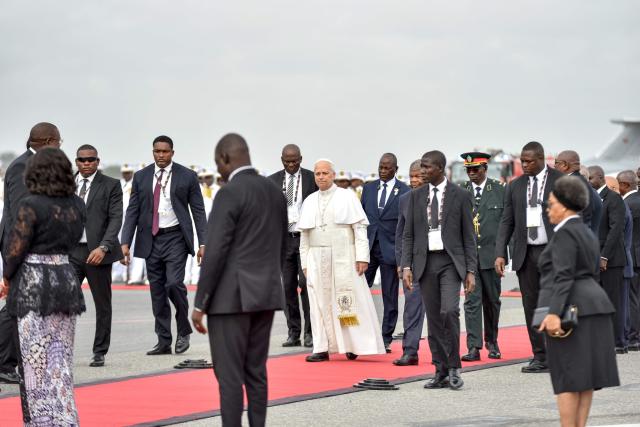 Pope Leo XIV (C) walks on the red carpet towards the plane aheaf of his departure from the "4 de Fevereiro" Luanda International Airport in Luanda on the ninth day of an 11-day apostolic journey to Africa, on April 21, 2026. (Photo by Julio PACHECO NTELA / AFP)