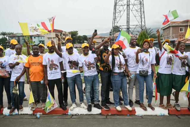 Residents stand next to the road on the route where Pope Leo XIV's motorcade will drive past after his arrival in Malabo on the ninth day of an 11-day apostolic journey to Africa, on April 21, 2026. (Photo by Alberto PIZZOLI / AFP)
