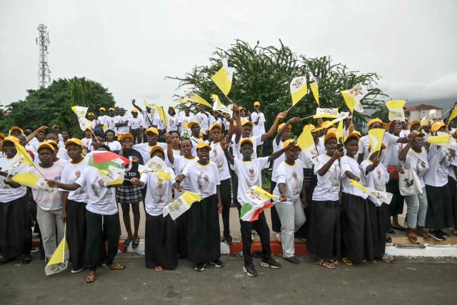 Residents stand next to the road on the route where Pope Leo XIV's motorcade will drive past after his arrival in Malabo on the ninth day of an 11-day apostolic journey to Africa, on April 21, 2026. (Photo by Alberto PIZZOLI / AFP)