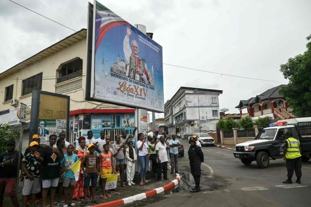 Residents stand next to the road on the route where Pope Leo XIV's motorcade will drive past after his arrival in Malabo on the ninth day of an 11-day apostolic journey to Africa, on April 21, 2026. (Photo by Alberto PIZZOLI / AFP)