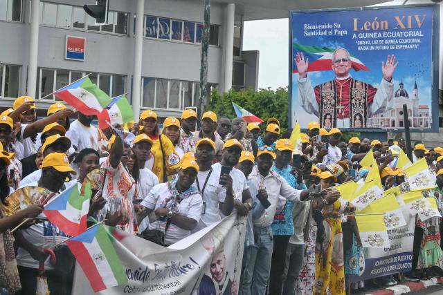 Residents stand next to the road on the route where Pope Leo XIV's motorcade will drive past after his arrival in Malabo on the ninth day of an 11-day apostolic journey to Africa, on April 21, 2026. (Photo by Alberto PIZZOLI / AFP)