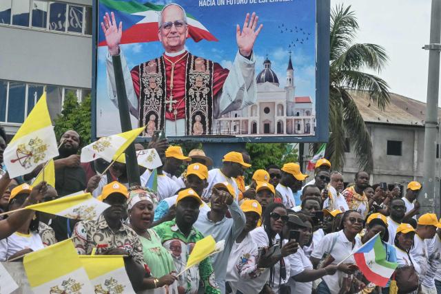Residents stand next to the road on the route where Pope Leo XIV's motorcade will drive past after his arrival in Malabo on the ninth day of an 11-day apostolic journey to Africa, on April 21, 2026. (Photo by Alberto PIZZOLI / AFP)