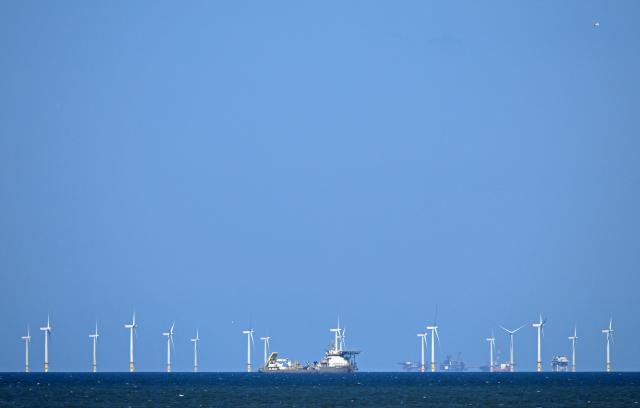 Offshore support vessel and cable layer, MV Ndeavor, operates in the vicinity of The Rhyl Flats offshore wind farm in the Irish Sea, pictured from the beach at Abergele in north Wales on April 21, 2026. Britain's government on April 21, 2026, unveiled plans to accelerate its clean energy drive after oil and gas prices soared in the wake of the US-Iran war. Placing solar panels and wind turbines on industrial and railway sites could power about five million homes, the Labour government said in a statement. (Photo by Paul ELLIS / AFP)