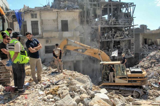 Members of the civil defence look on as a digger removes the rubble of buildings destroyed in Israeli strikes, as they search for survivors buried underneath continues in the southern Lebanese coastal city of Tyre on April 21, 2026. Israeli defence minister said on April 21 that his country's campaign in Lebanon relied on both military and diplomatic pressure to disarm Iran-allied Hezbollah. Though a truce between Israel and Lebanon took effect on April 17, Israeli troops are still present and actively fighting Hezbollah militants in Lebanon's south. (Photo by Mahmoud ZAYYAT / AFP)